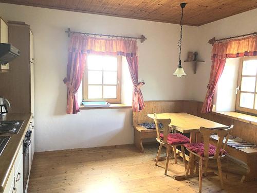eine Küche mit einem Tisch, Stühlen und Fenstern in der Unterkunft Ferienhaus Haring in Kitzeck im Sausal