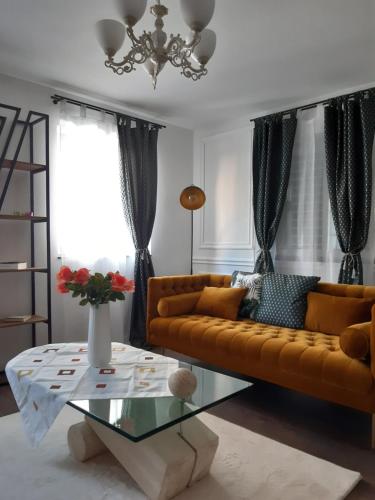 uma sala de estar com um sofá amarelo e uma mesa de vidro em Rome Apartment em Rheineck