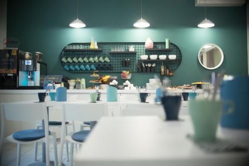 a restaurant with blue walls and white tables and chairs at Hotel Civitas in Sopron