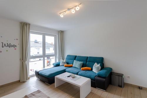 a living room with a blue couch and a table at Pension am See in Kremmen