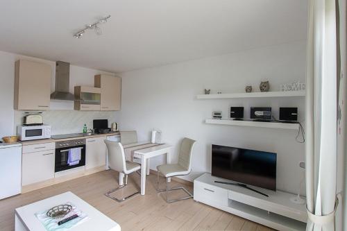 a kitchen with a table and chairs and a television at Pension am See in Kremmen