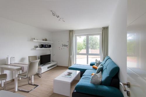 a living room with a blue couch and a table at Pension am See in Kremmen