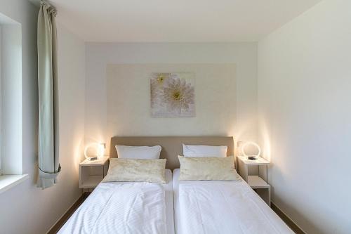 two beds in a white room with two lamps at Pension am See in Kremmen