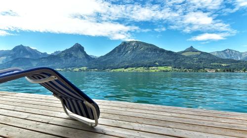 a bench sitting on a dock overlooking a body of water at Hotel Weisser Hirsch in St. Wolfgang