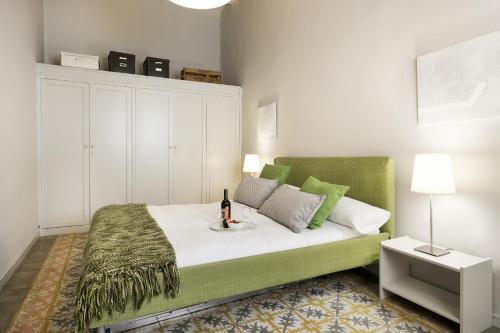 a bedroom with a green bed with a bottle of wine on it at Ola Living Gaudi in Barcelona