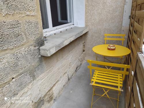 una mesa amarilla y dos sillas sentadas junto a una ventana en SUD ET DETENTE, en Gallargues-le-Montueux