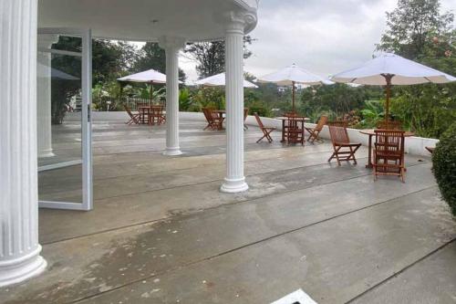 a patio with tables and chairs with umbrellas at RedDoorz Plus @ Megamendung Puncak 2 in Bogor