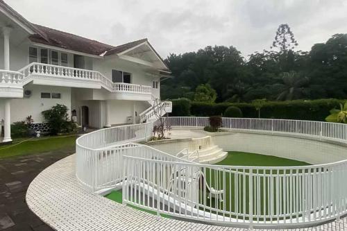 a white house with a white fence around a yard at RedDoorz Plus @ Megamendung Puncak 2 in Bogor