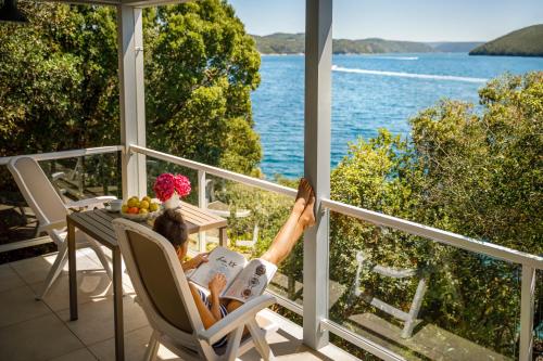 Eine Frau, die auf einem Stuhl liegt und ein Buch auf einem Balkon liest. in der Unterkunft Maistra Camping Koversada Naturist Mobile homes in Vrsar