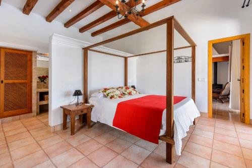 a bedroom with a canopy bed with a red blanket at Can Palau in Sant Joan de Labritja