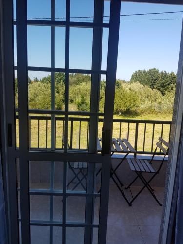 a view from the front door of a porch with chairs at Hostal Xaraiba in Sanxenxo