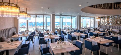 a restaurant with tables and chairs and windows at Royal Blue Hotel in Dubrovnik