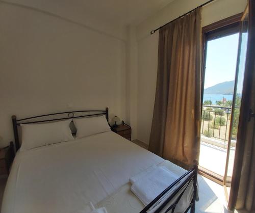 1 dormitorio con cama y ventana grande en Domaine Papakonstantis Apartments To Let, en Skoutari