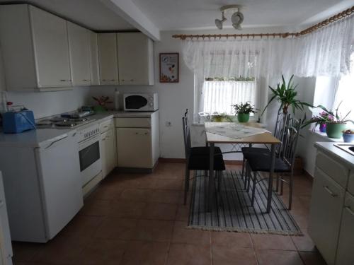 a kitchen with white cabinets and a table with chairs at Ferienhaus Johanna in Weischlitz