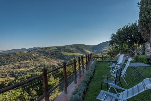 a patio with chairs and a table and a view of the mountains at Castellinuzza in Greve in Chianti