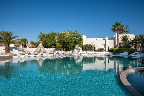- une piscine d'eau bleue dans un complexe dans l'établissement AMĀRIA Beach Resort by NOMÉE Hospitality Group, à Kamari