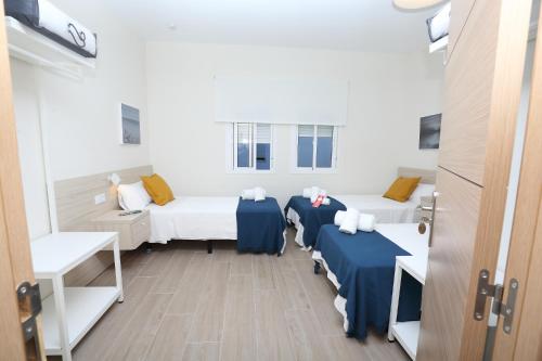 a room with three beds with blue sheets and a door at H.PALMONES in Palmones