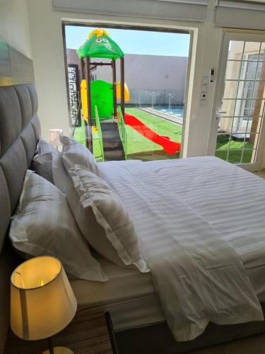 a bedroom with a bed with a playground in the background at Al Somow Chalets in Dahaban