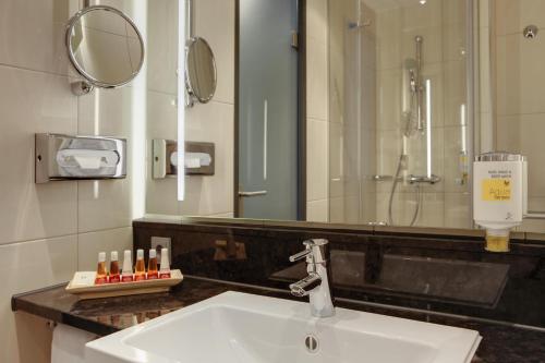 a bathroom with a sink and a shower and a mirror at IntercityHotel Hannover in Hannover