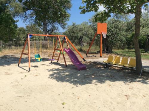 un parque infantil con tobogán y sillas en la arena en Pension Karadolas Rachoni, en Skala Rachoniou
