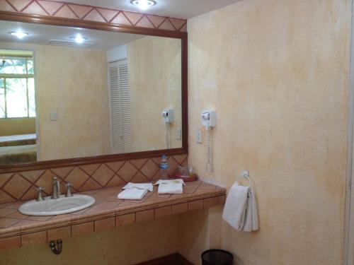 uma casa de banho com um lavatório e um espelho grande em Hotel Calli em Santo Domingo Tehuantepec