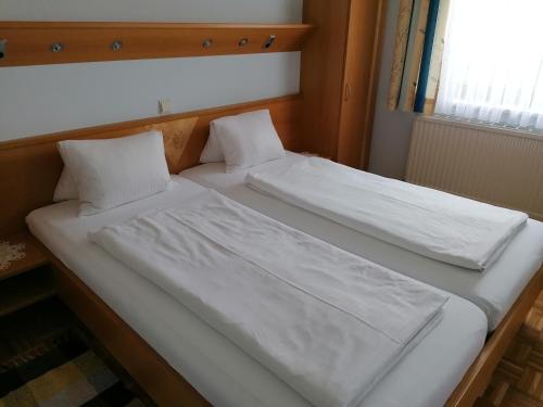 two beds with white sheets and pillows in a room at Kirchenwirt Mirth in Eltendorf