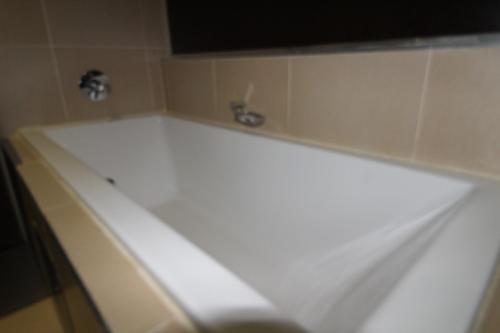 a white bath tub in a bathroom with a sink at Alcazaba Hotel in Johannesburg