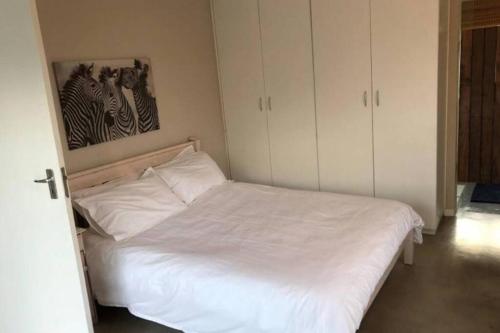 Un dormitorio con una cama blanca y una pintura en la pared en Staples House - Living The Breede, en Malgas