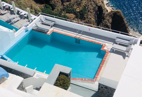 a swimming pool on the side of a house with the ocean at Loucas on the Cliff in Fira