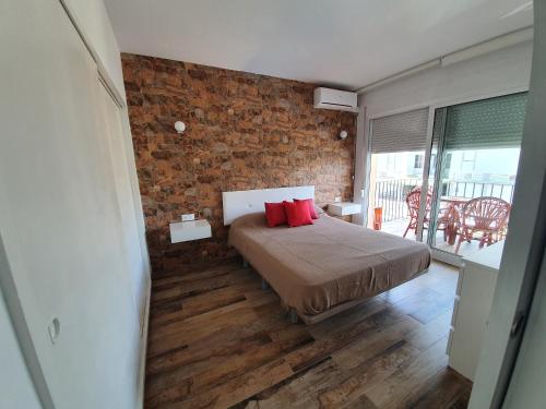トレモリノスにあるApartamento Primera Línea de Playaのレンガの壁のベッドルーム1室、赤い枕付きのベッド1台が備わります。