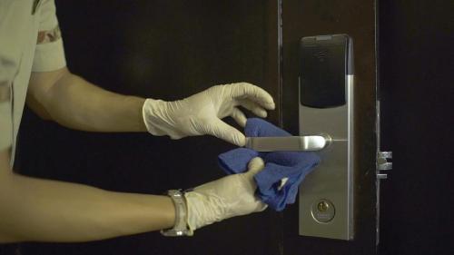 a person wearing gloves and holding a blue cloth on a door at Amaris Hotel Darmo Surabaya in Surabaya