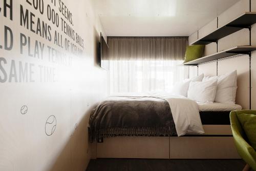 a bedroom with a bed with white pillows and a window at Hektor Container Hotel in Tallinn