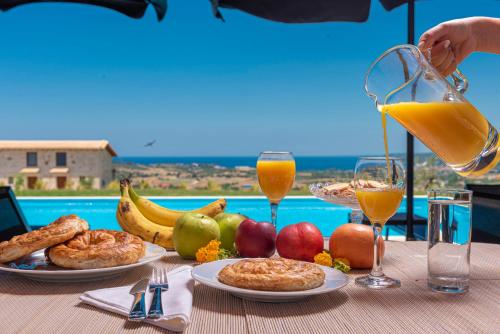 a table with plates of food and glasses of orange juice at Mint Retreat Suites in Kalandra