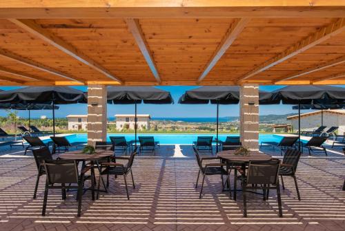 a patio with tables and chairs and umbrellas at Mint Retreat Suites in Kalandra
