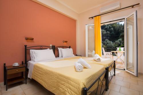 a bedroom with two beds and a balcony at Odysseus Apartments By Hotelius in Agios Gordios