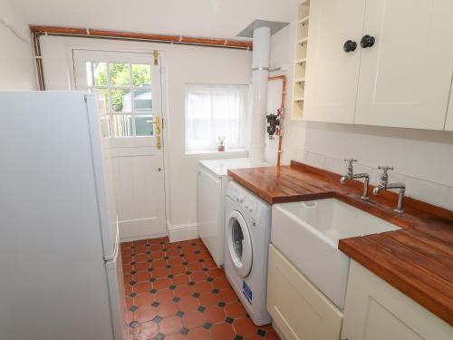 a kitchen with a sink and a washing machine at Bawbee Cottage in Denbigh