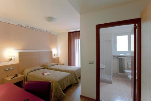 a hotel room with two beds and a bathroom at Alphotel Milano in Andalo