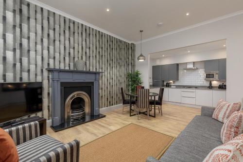 a living room with a fireplace and a kitchen at Destiny Scotland - Princes Street Residence in Edinburgh