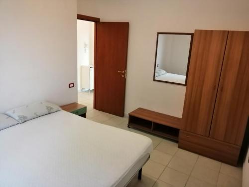 1 dormitorio con cama, tocador y espejo en Appartamento indipendete VillaRosa, en Alba Adriatica