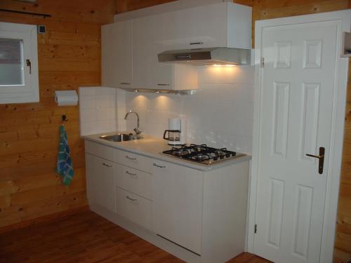 eine weiße Küche mit einer Spüle und einem Herd in der Unterkunft Chalet 66 in Porlezza