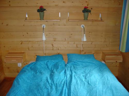 ein Schlafzimmer mit einem Bett mit blauer Bettwäsche und zwei Lichtern in der Unterkunft Chalet 66 in Porlezza