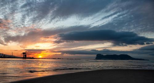 a sunset on the beach with a lighthouse in the distance at H.PALMONES in Palmones