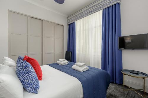 a bedroom with a bed with blue curtains and a tv at Destiny Scotland - Princes Street Residence in Edinburgh