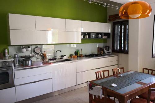 a kitchen with white cabinets and a table with chairs at Villa Tiziana in Monreale