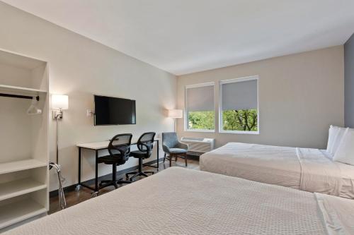 a hotel room with two beds and a desk at Extended Stay America Premier Suites - Austin - Austin Airport in Austin