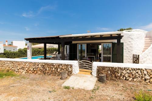 a house with a stone wall next to a pool at Pura Vida in Binibeca