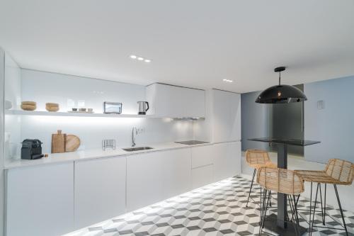 a kitchen with white cabinets and two bar stools at Casa Boma Lisboa - Duplex Apartment In The Heart Of Lisbon - Arroios I in Lisbon