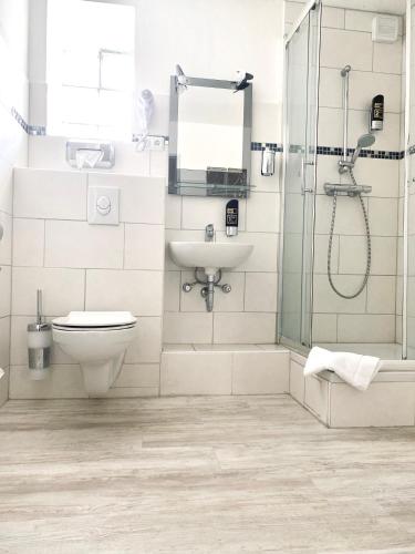 a bathroom with a toilet and a sink and a shower at Hotel Auerhahn in Grevenkrug