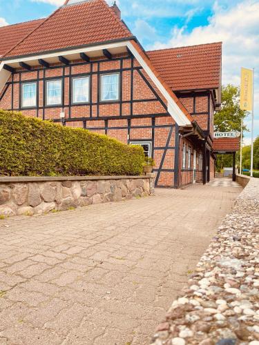a brown building with a red roof and a brick road at Hotel Auerhahn in Grevenkrug