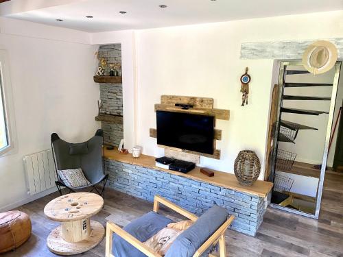 a living room with a couch and a tv at Maison les pieds dans l'eau in Villefort